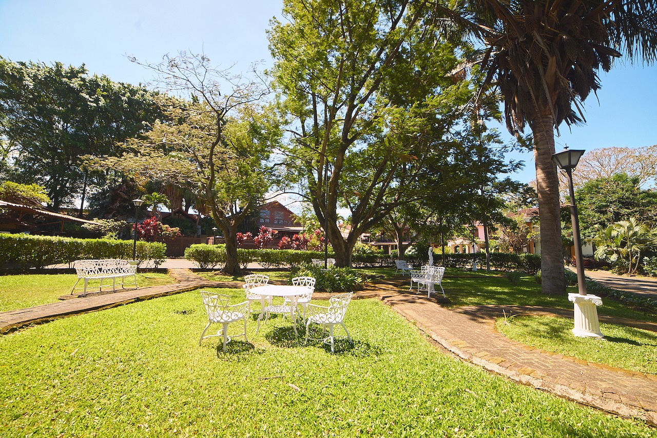 Salon de jardin avec chaises blanches sous les arbres à l'hôtel El Rodeo Estancia, au Costa Rica