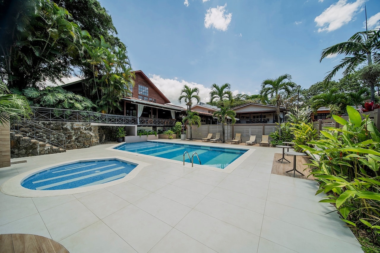 Grande piscine bordée de palmiers et de jardins tropicaux à l'hôtel El Rodeo Estancia, au Costa Rica