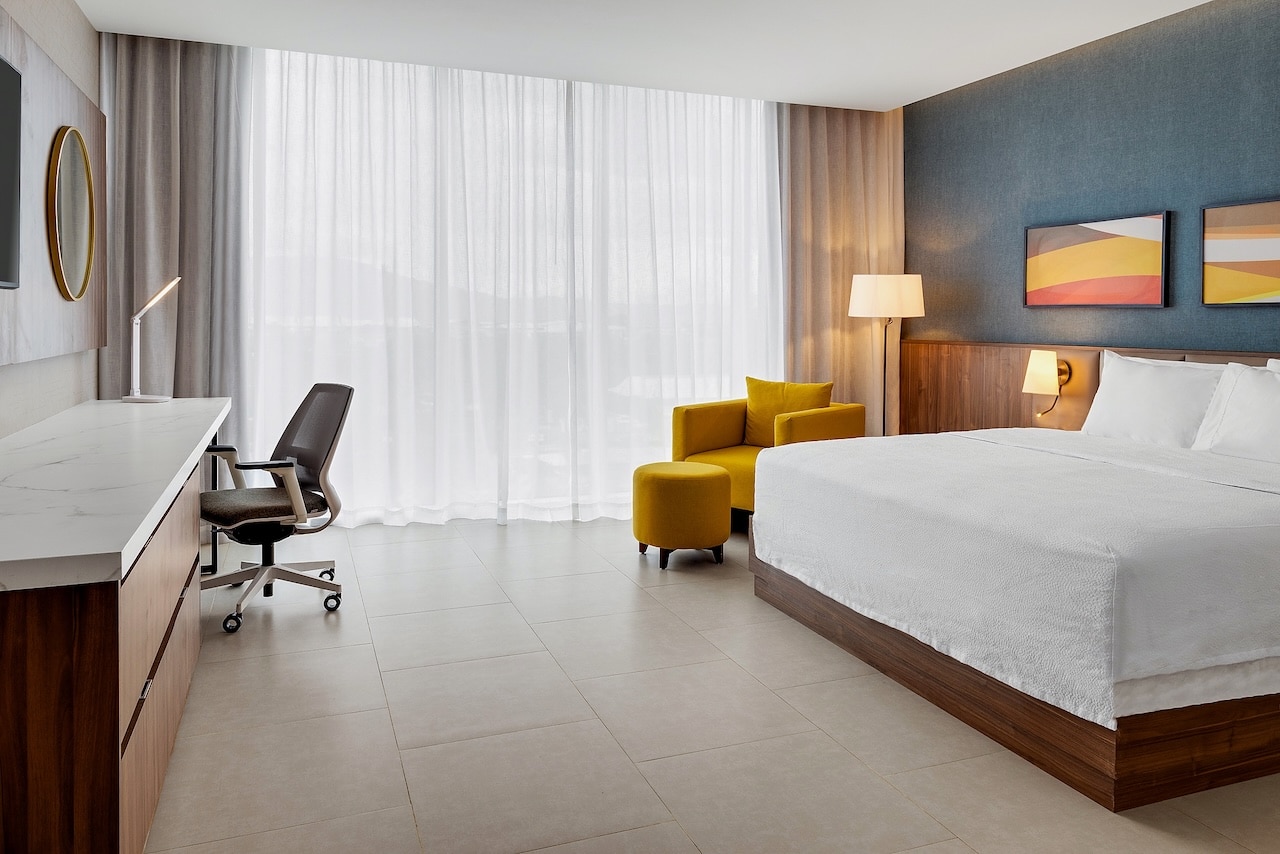 Chambre avec lit king et fauteuil jaune au Hilton Garden Inn San Jose Airport City Mall, Costa Rica