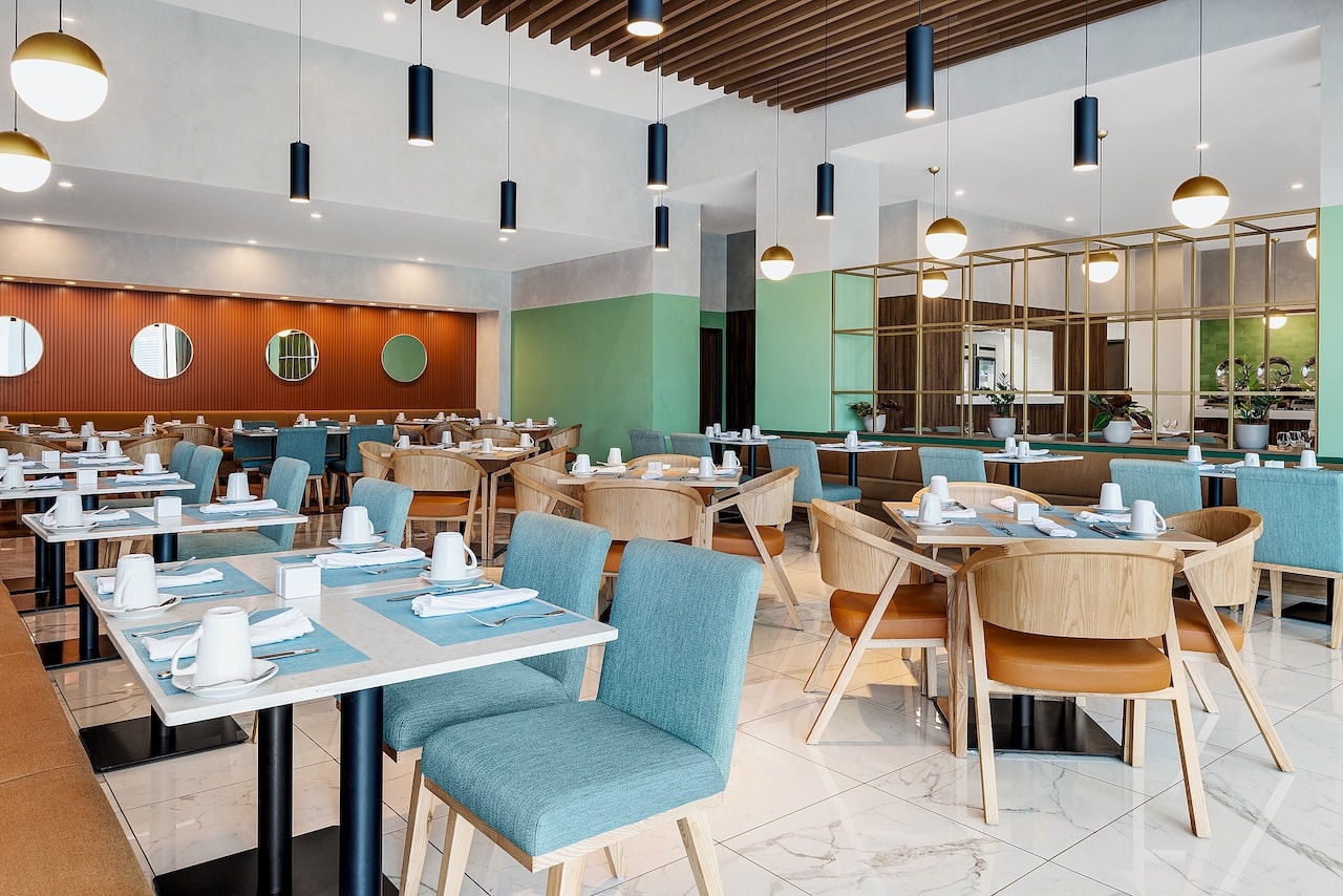 Salle du restaurant avec tables et miroirs au Hilton Garden Inn San Jose Airport City Mall, Costa Rica